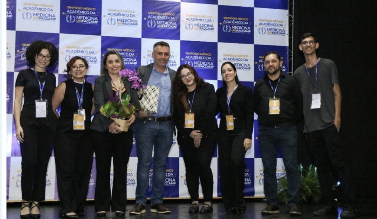 Equipe e convidados diante do painel do Simpósio Médico Acadêmico